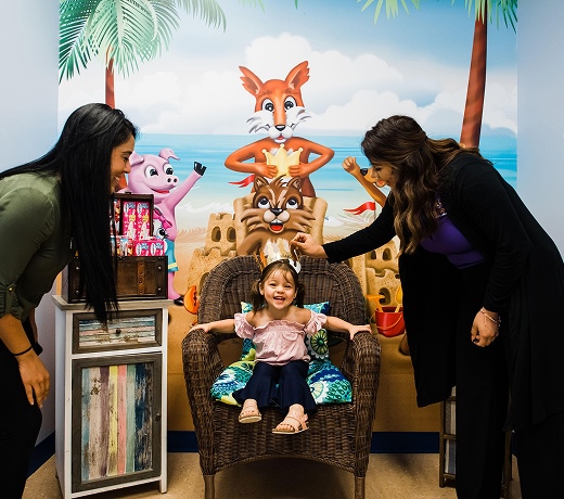 A young patient in the photo booth at Smile Magic with two staff members