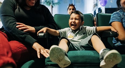 Child laughing in a dental chair while their family looks on