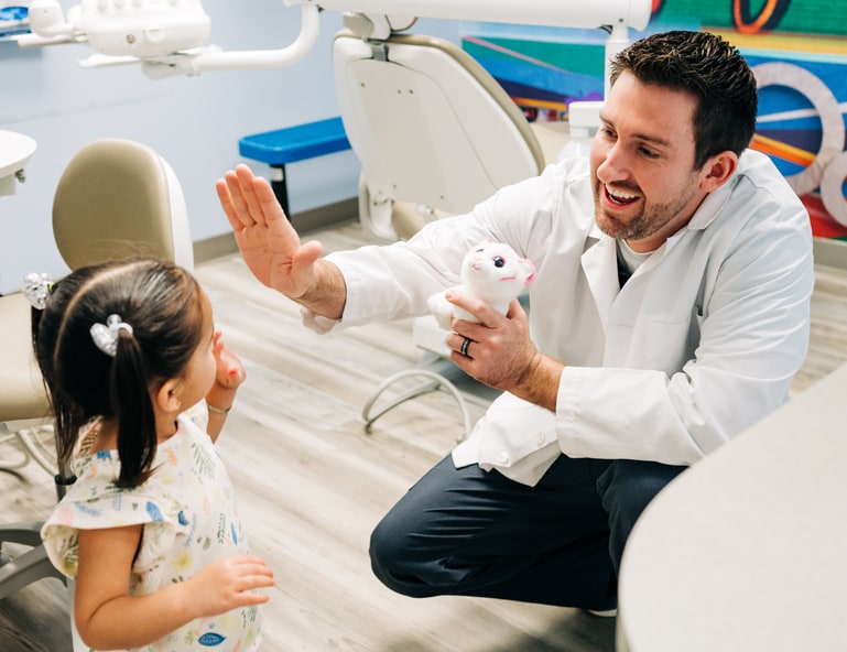 Dentist high-fiving a young girl after her appointment