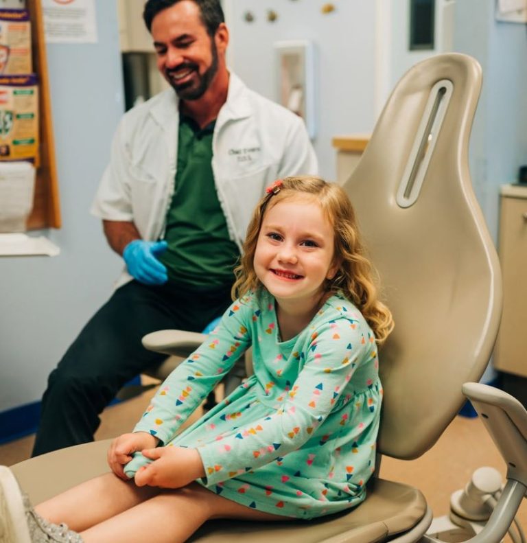Dentist smiling with a young patient in the exam chair at Smile Magic