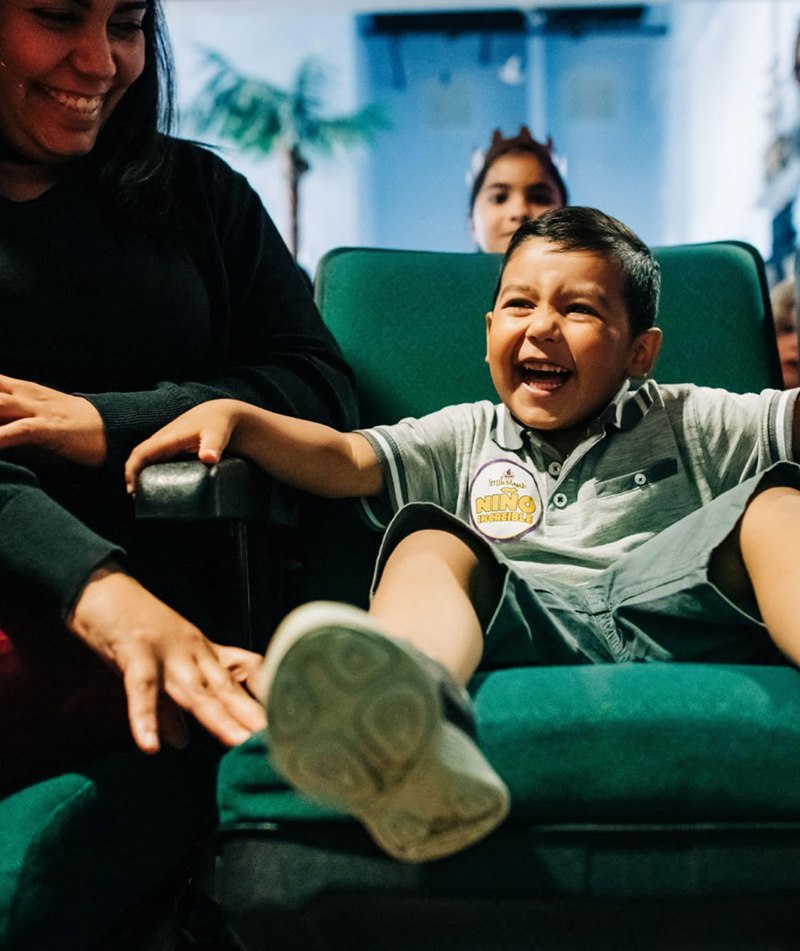 Child laughing in a dental chair while their family looks on