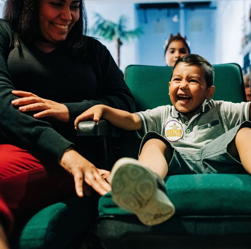 Child laughing in a dental chair while their family looks on