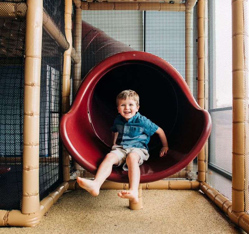 Child playing in the indoor play gym slide at Smile Magic