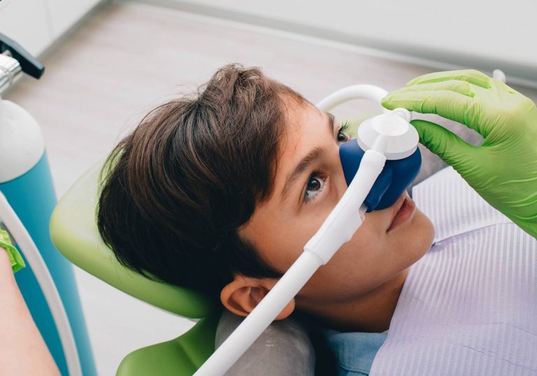 Child breathing nitrous oxide through a nasal mask in a dental chair