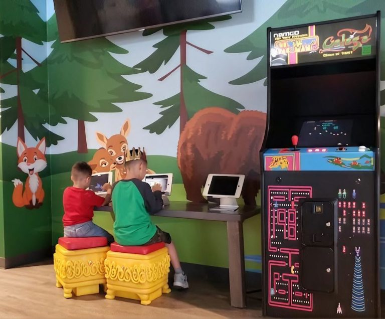 Children playing arcade games in the forest-themed game area at Smile Magic in Dyer, El Paso