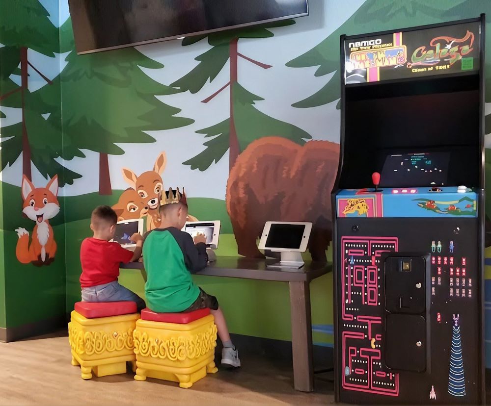 Children playing arcade games in the forest-themed game area at Smile Magic in Dyer, El Paso