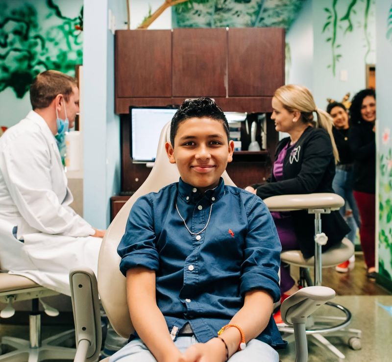 Teen patient in a jungle-themed treatment room at Smile Magic with family nearby