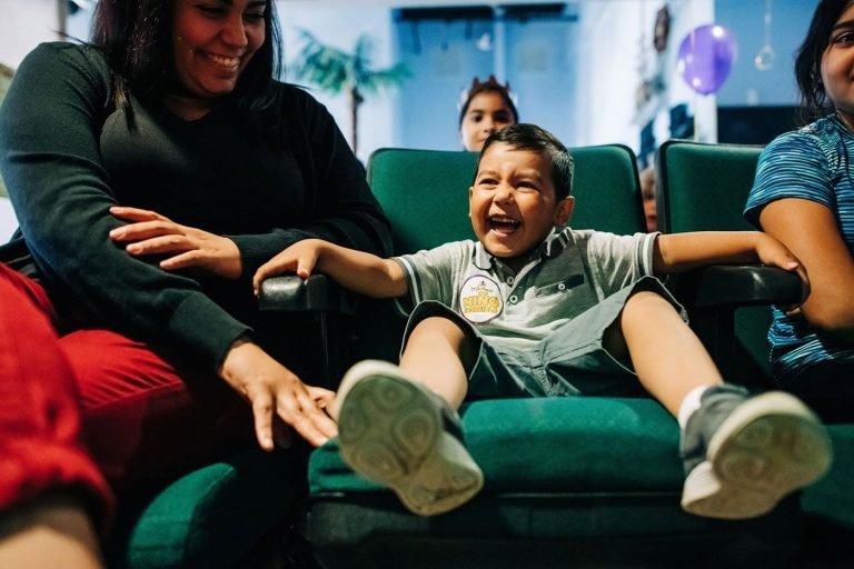 Child laughing in a dental chair while their family looks on
