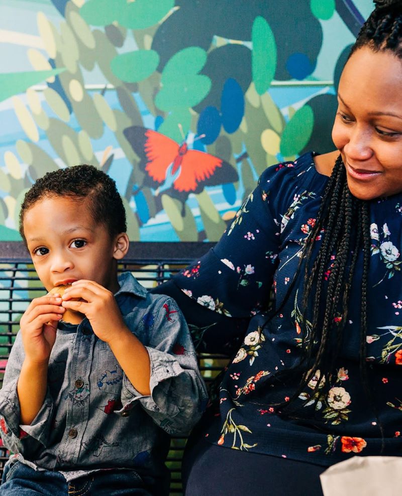 Young boy sitting outdoors with his mother