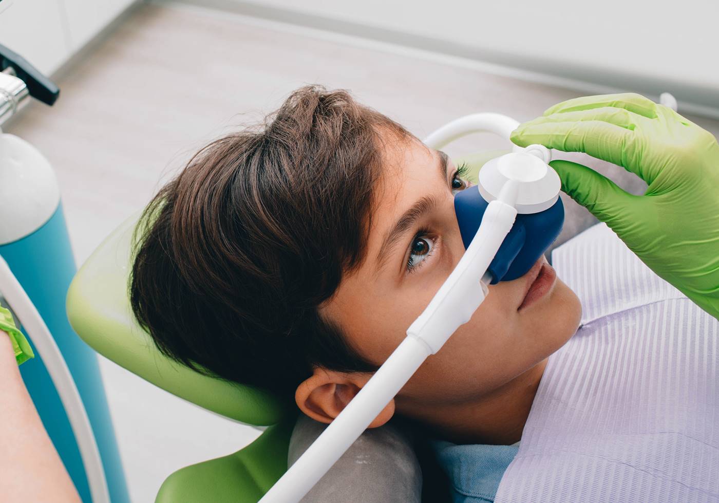 Child breathing nitrous oxide through a nasal mask in a dental chair